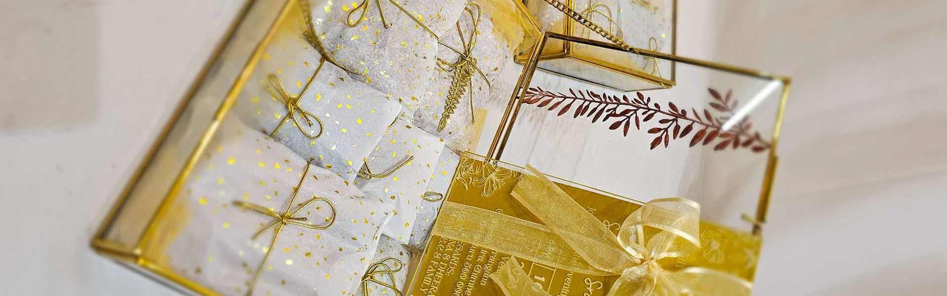 Decorative glass box with gold accents and gift-wrapped items inside.