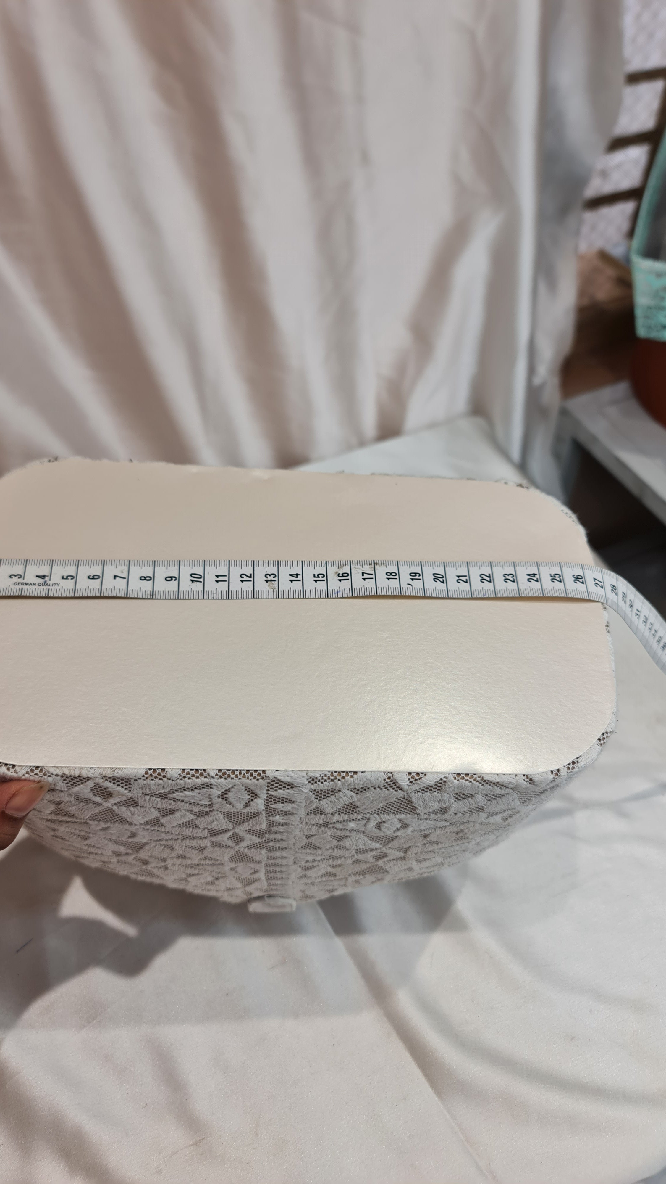 Close-up of a shoe with a measuring tape for size comparison, on a light fabric background.