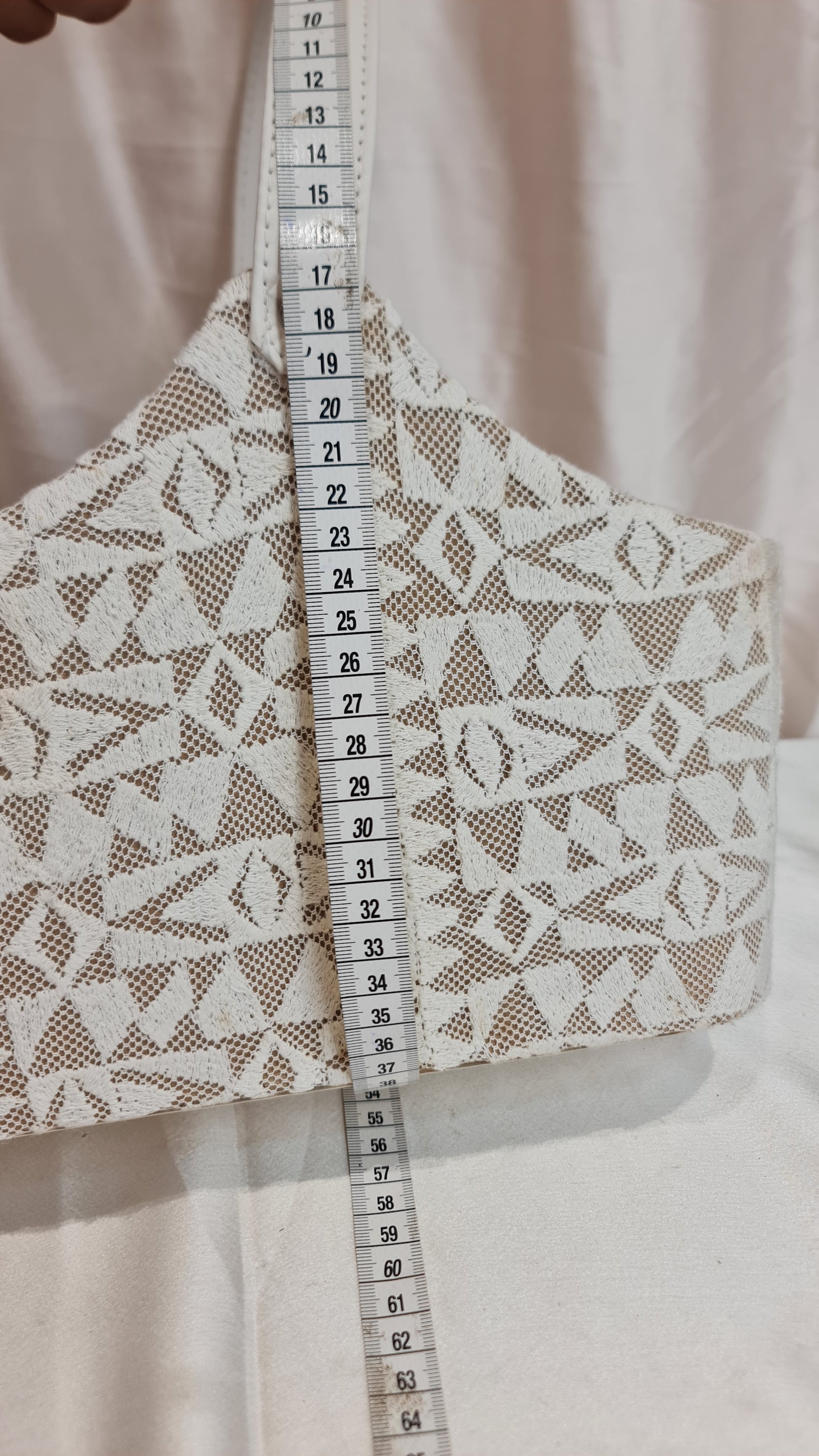 Lace fabric with a measuring tape showing dimensions on a light background