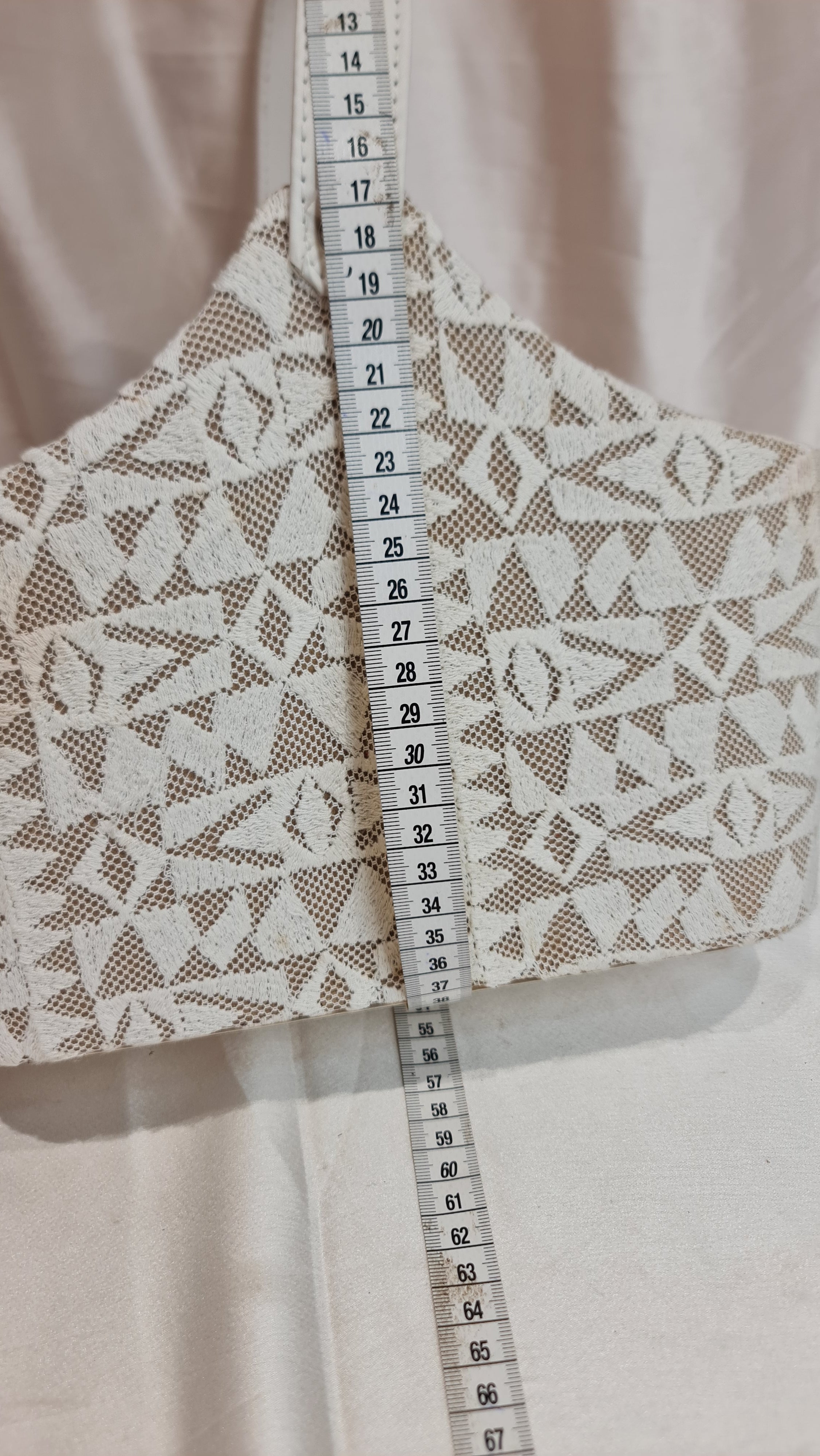 Lace fabric with a measuring tape showing dimensions on a light background