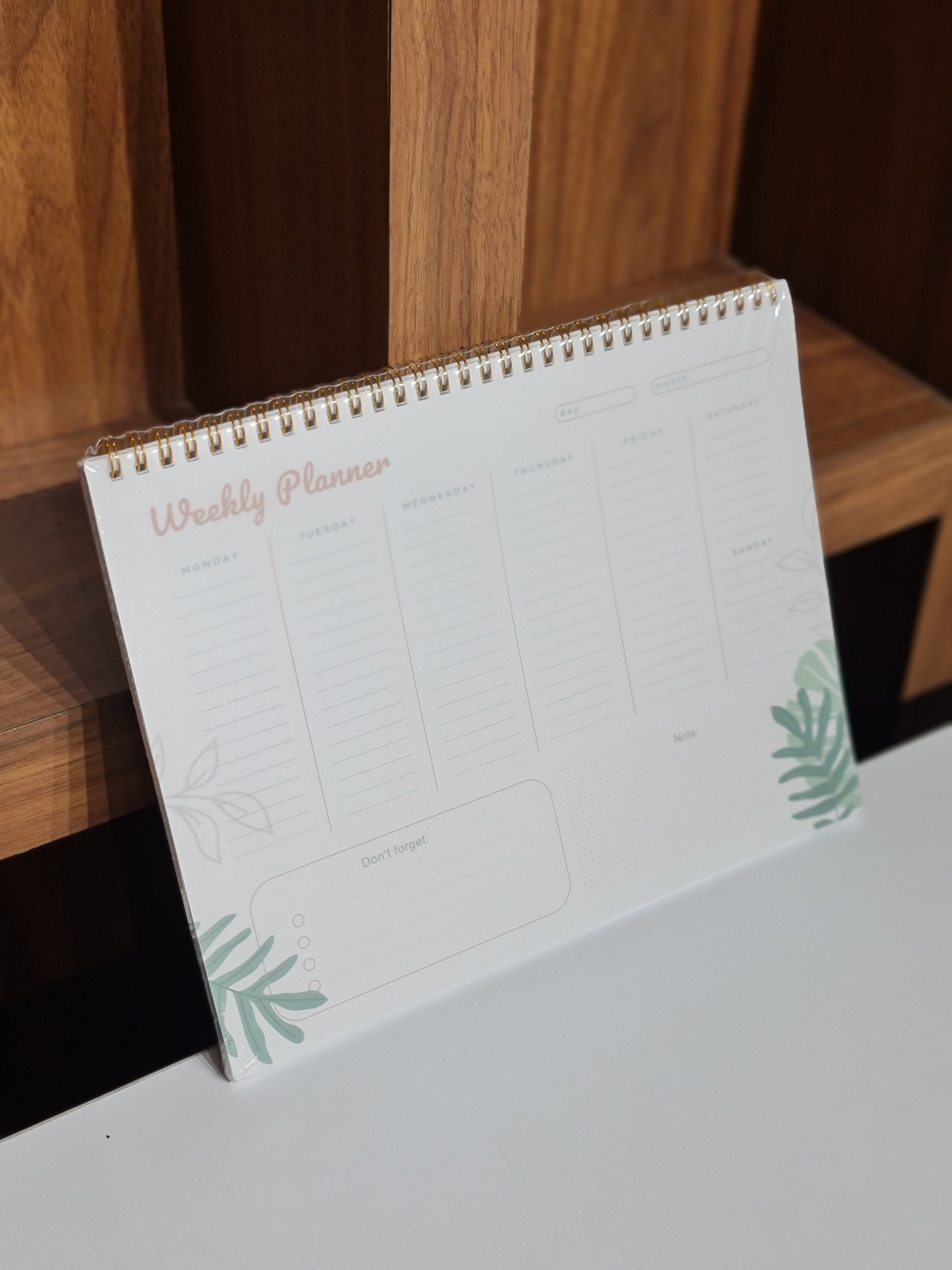 Weekly planner with plant designs on a wooden surface
