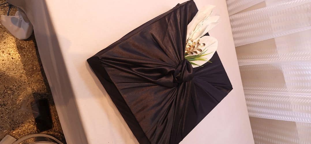 Black cushion with a floral arrangement on a white surface