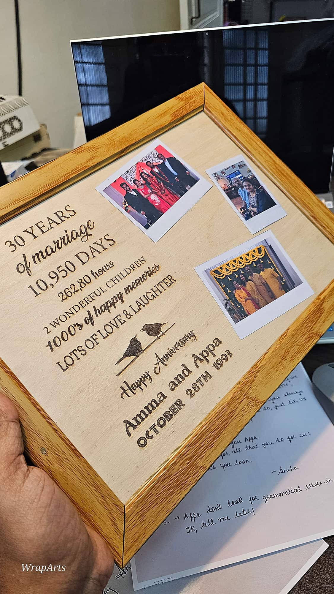 Wooden frame with anniversary details and Polaroid photos on a desk.