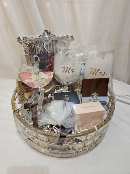 Gift basket with 'Mr' and 'Mrs' glasses, Starbucks card, and other items on a white background