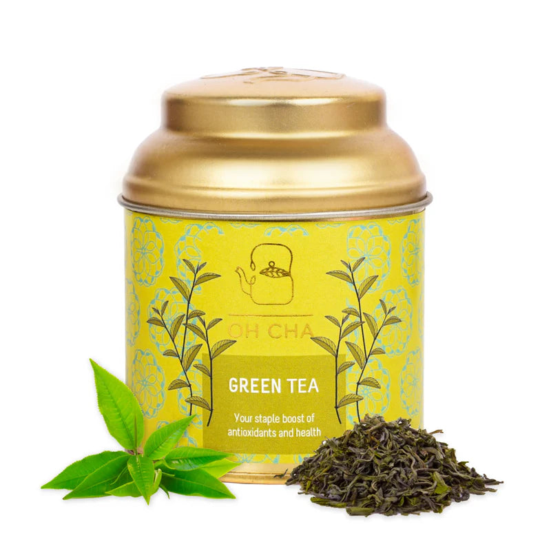 Gold tea canister with green tea leaves and packaging on a white background