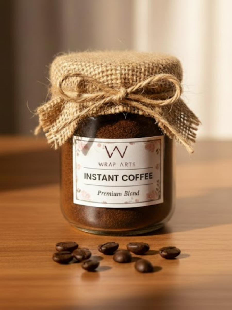 Jar of instant coffee with a burlap bow on a wooden surface, featuring Wrap Arts branding.