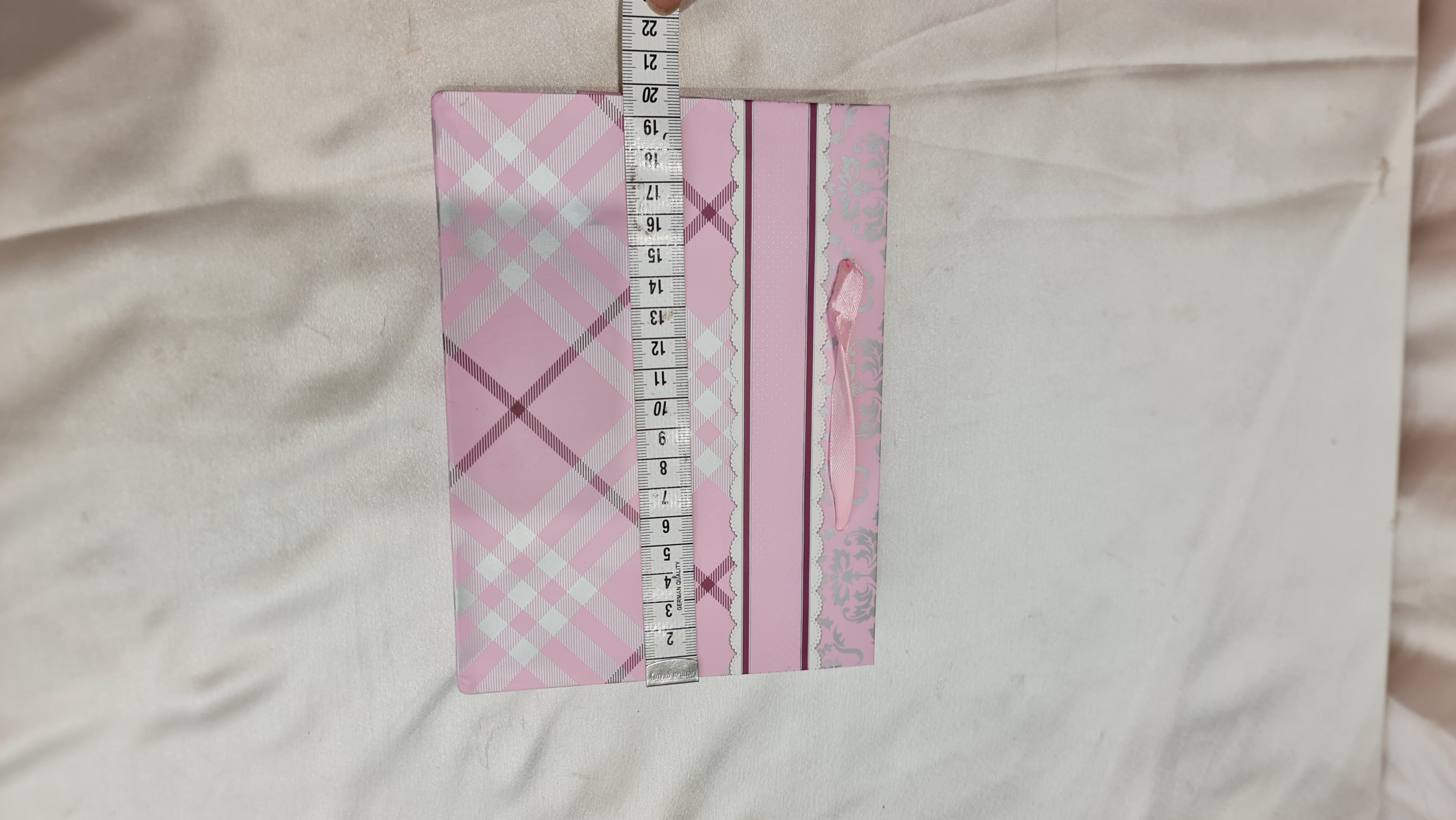 Pink and gray checkered fabric with a ruler for scale on a light pink background