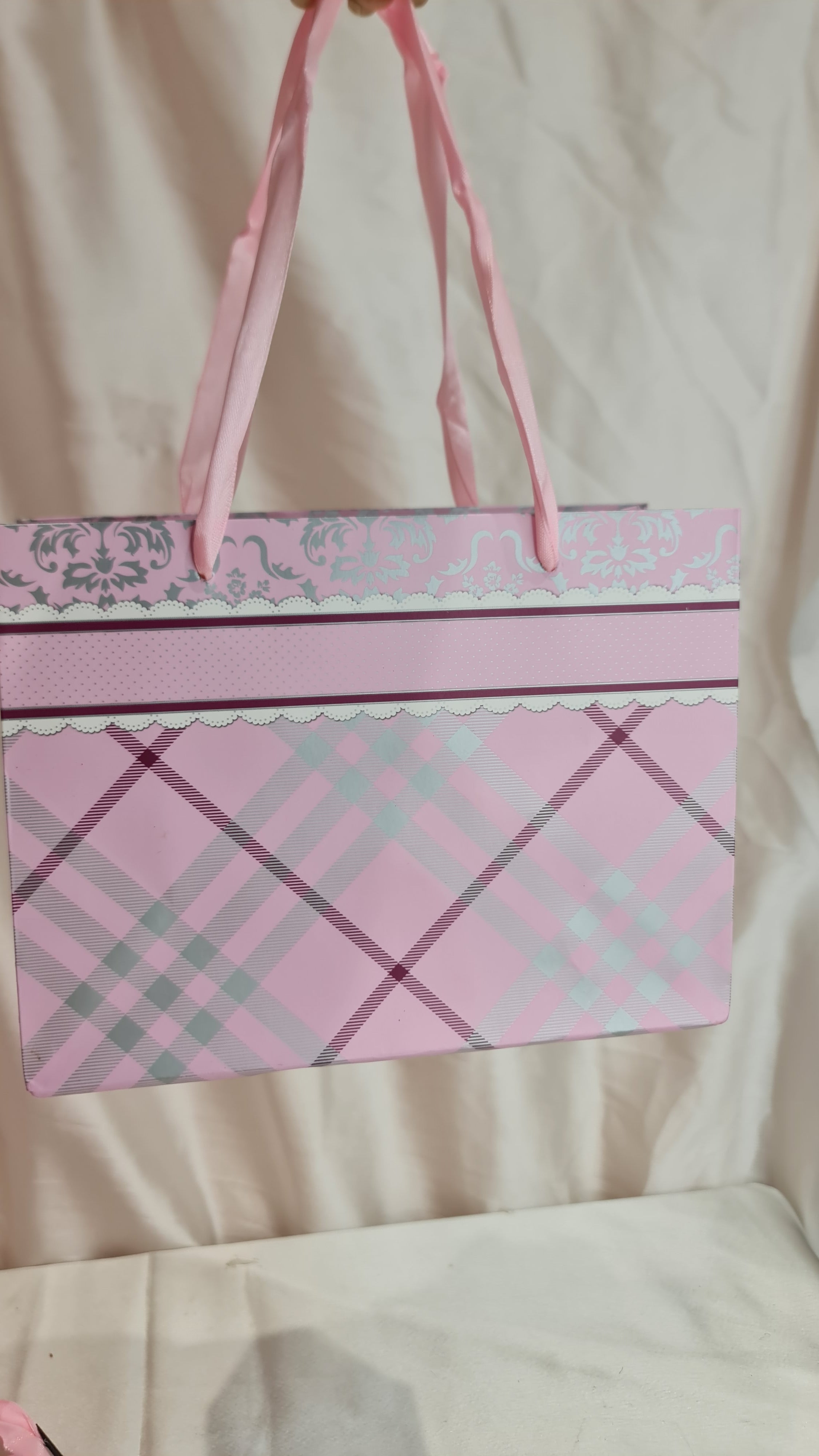 Pink plaid fabric with a decorative border on a light background