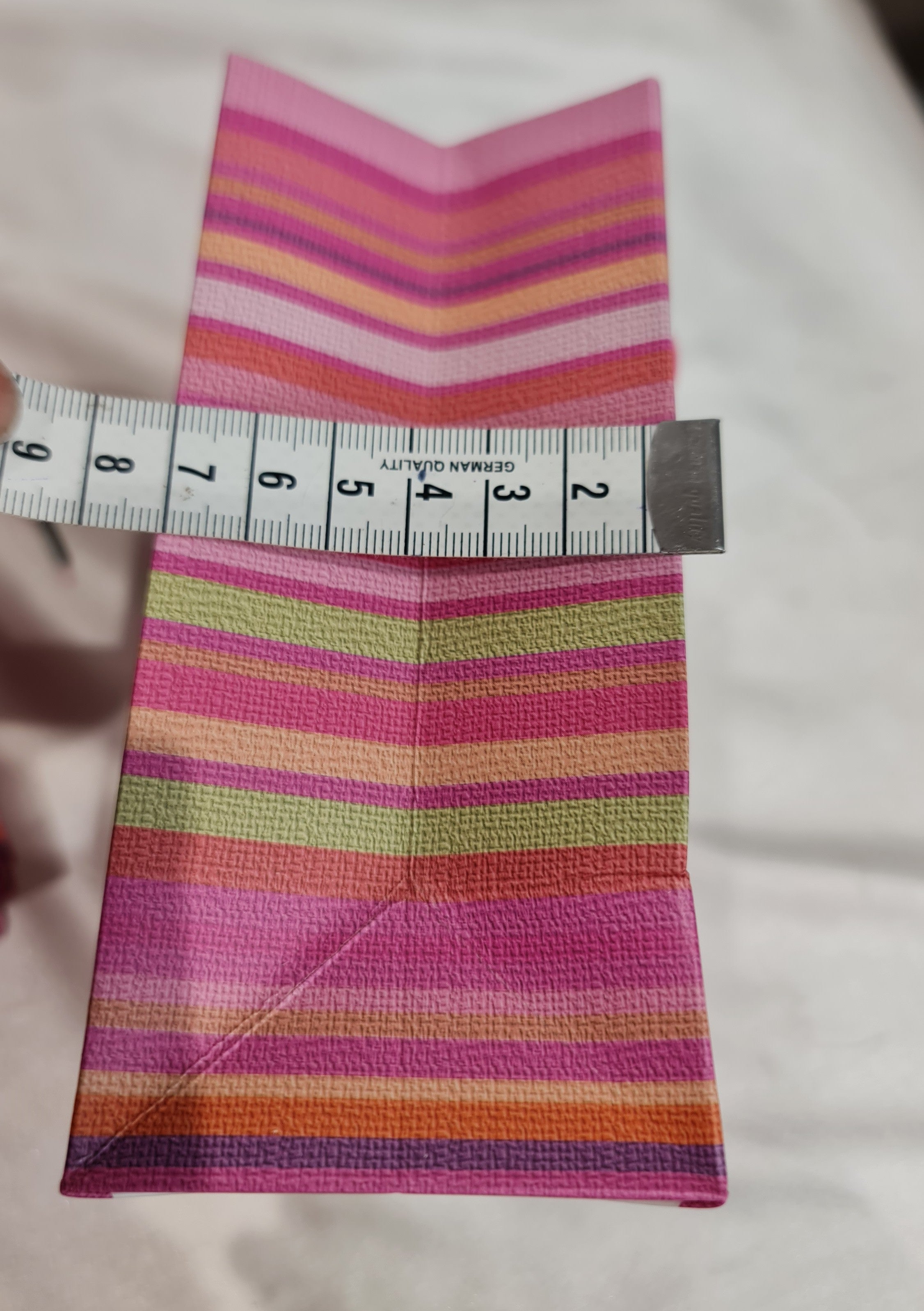 Multicolored striped fabric with a measuring tape for scale on a light background