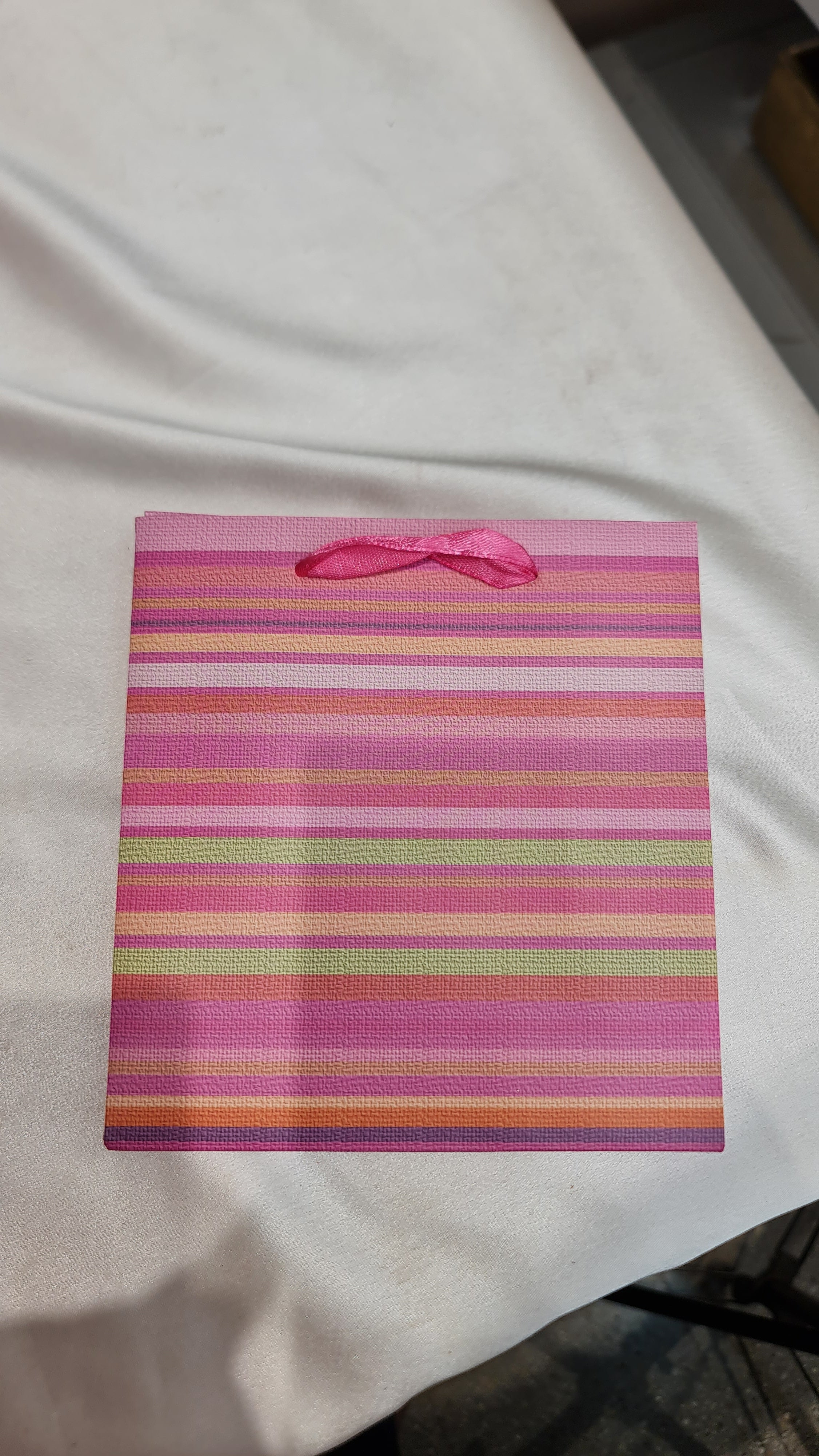 Striped fabric with a pink bow on a white surface