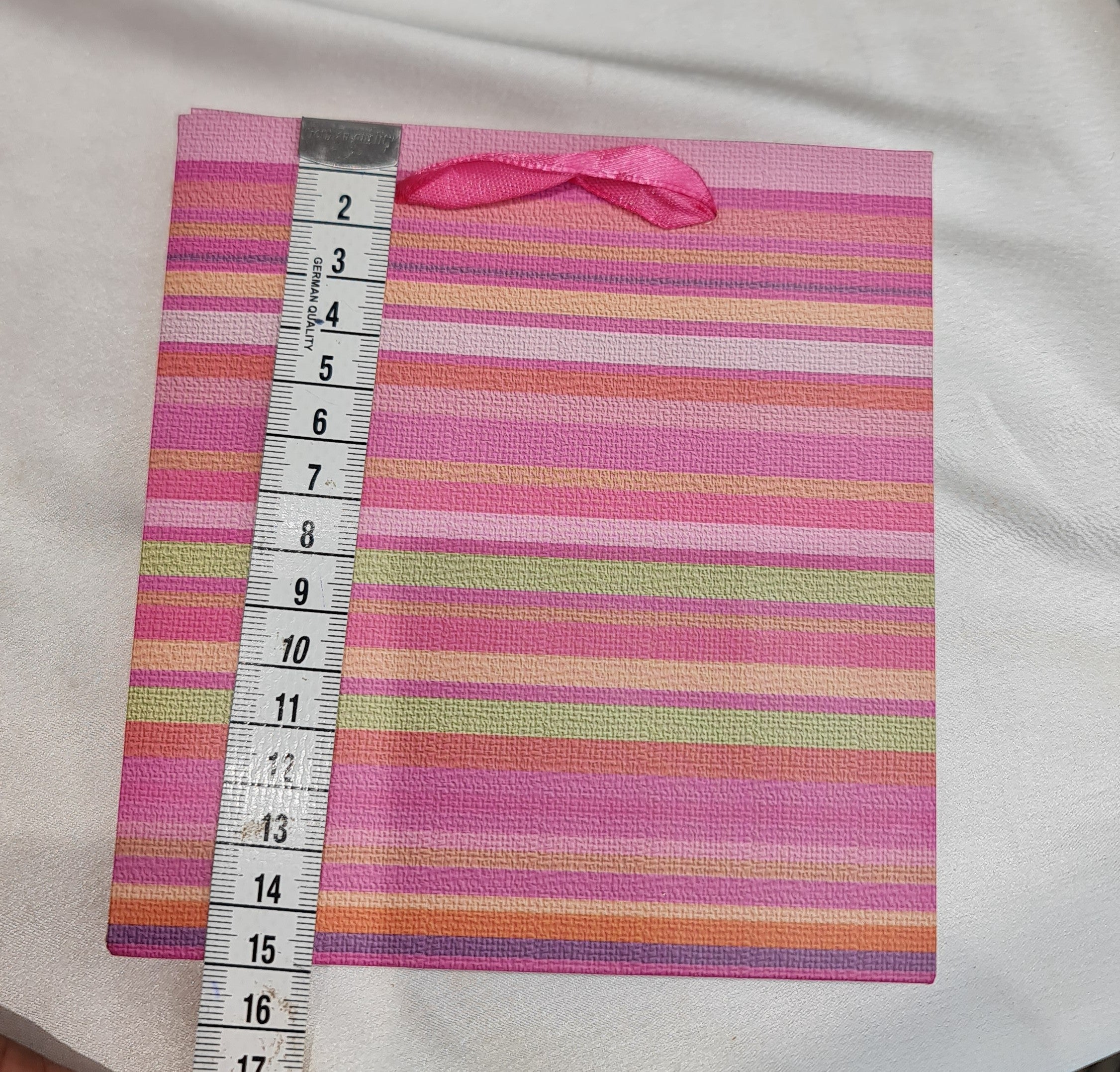 Striped fabric with a pink ribbon and measuring tape on a white background