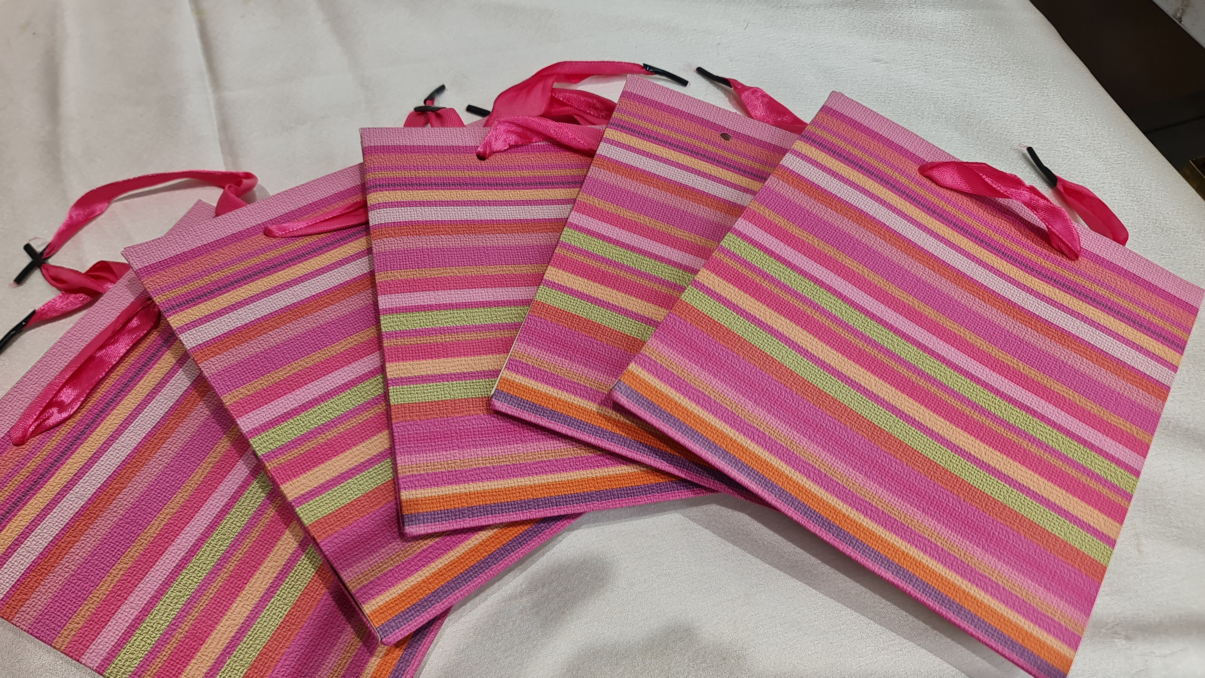 Set of pink striped bags with ribbons on a white background