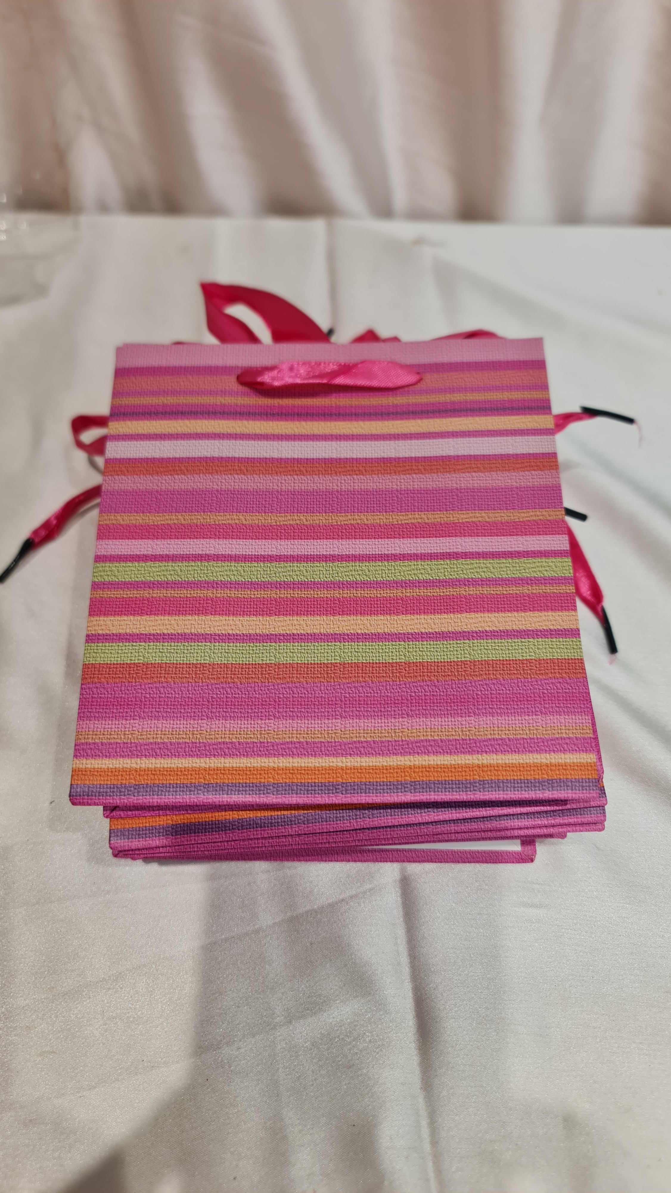 Colorful striped gift bag with ribbons on a light background