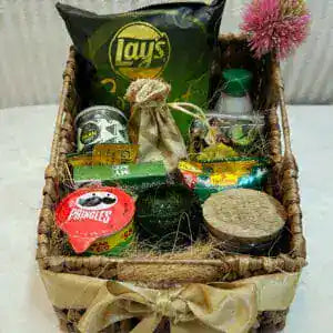 Wicker gift basket with snacks and items on a white surface