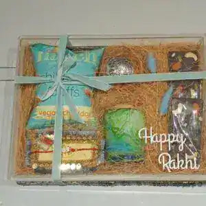 Gift basket with Rakhi and snacks on a white background
