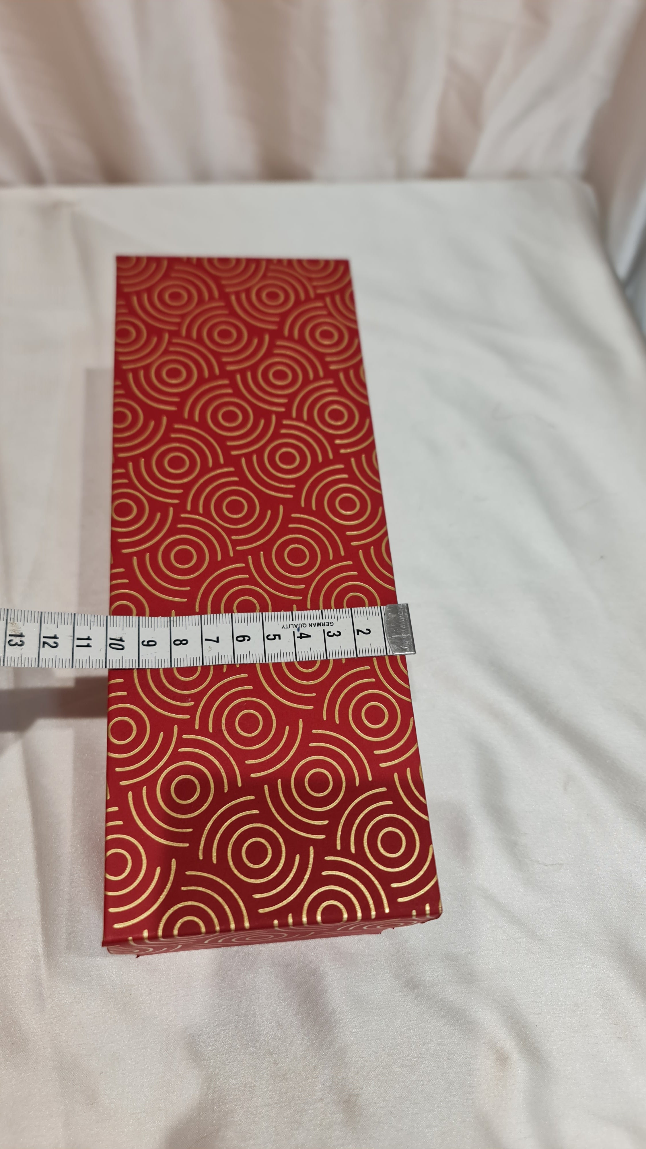 Red patterned fabric with a measuring tape on a white background