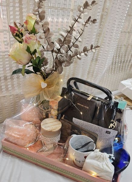 Table with a vase of flowers, handbag, and various items on a white surface.