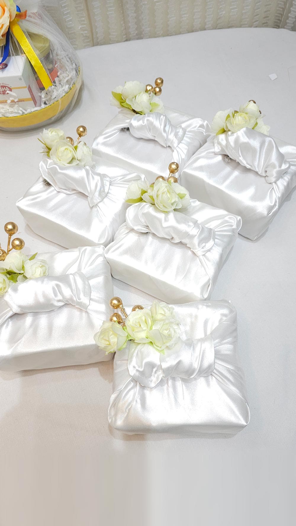 White satin boxes with floral decorations on a white surface