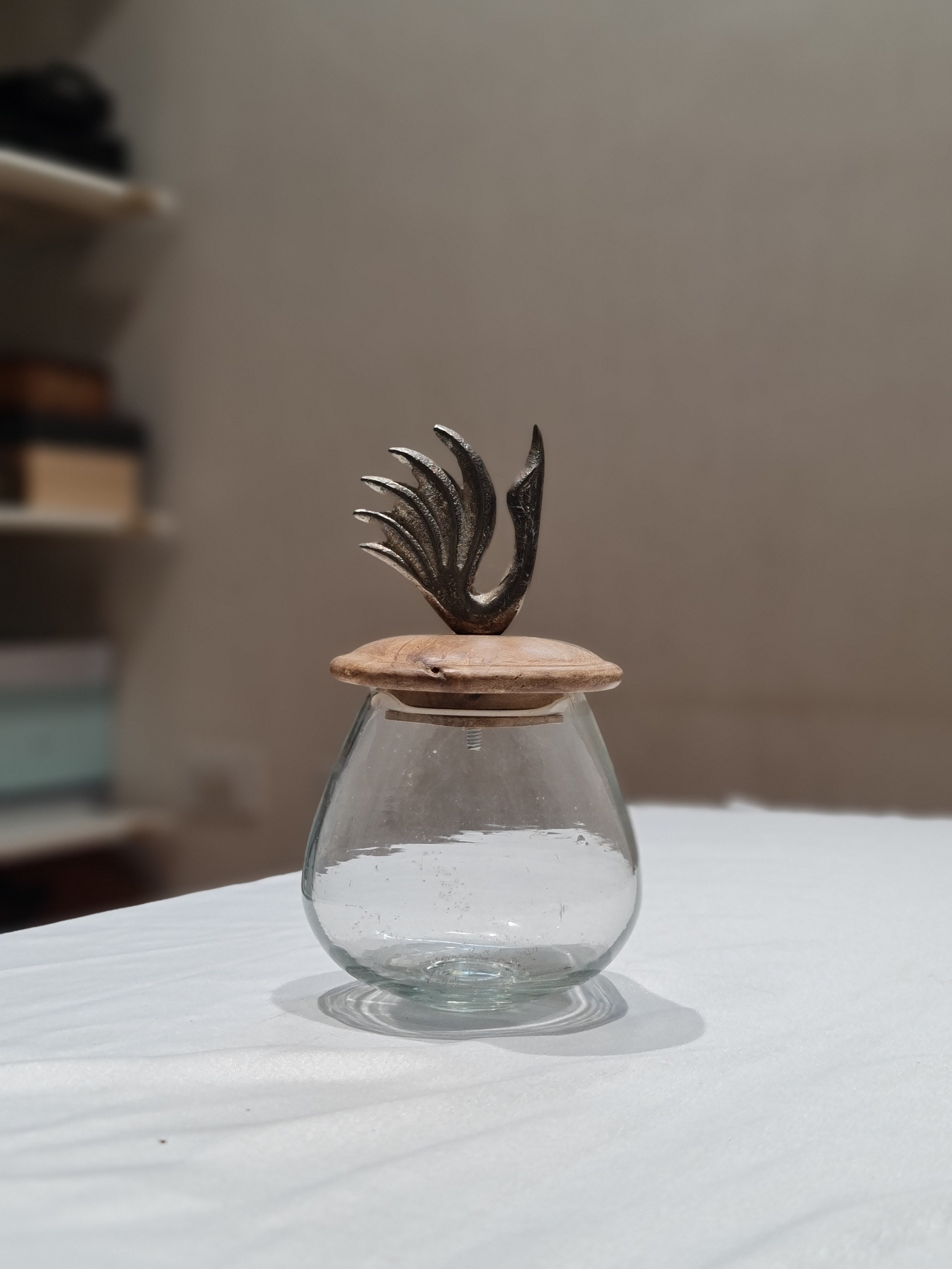 Glass bottle with a decorative metal wing on a white background