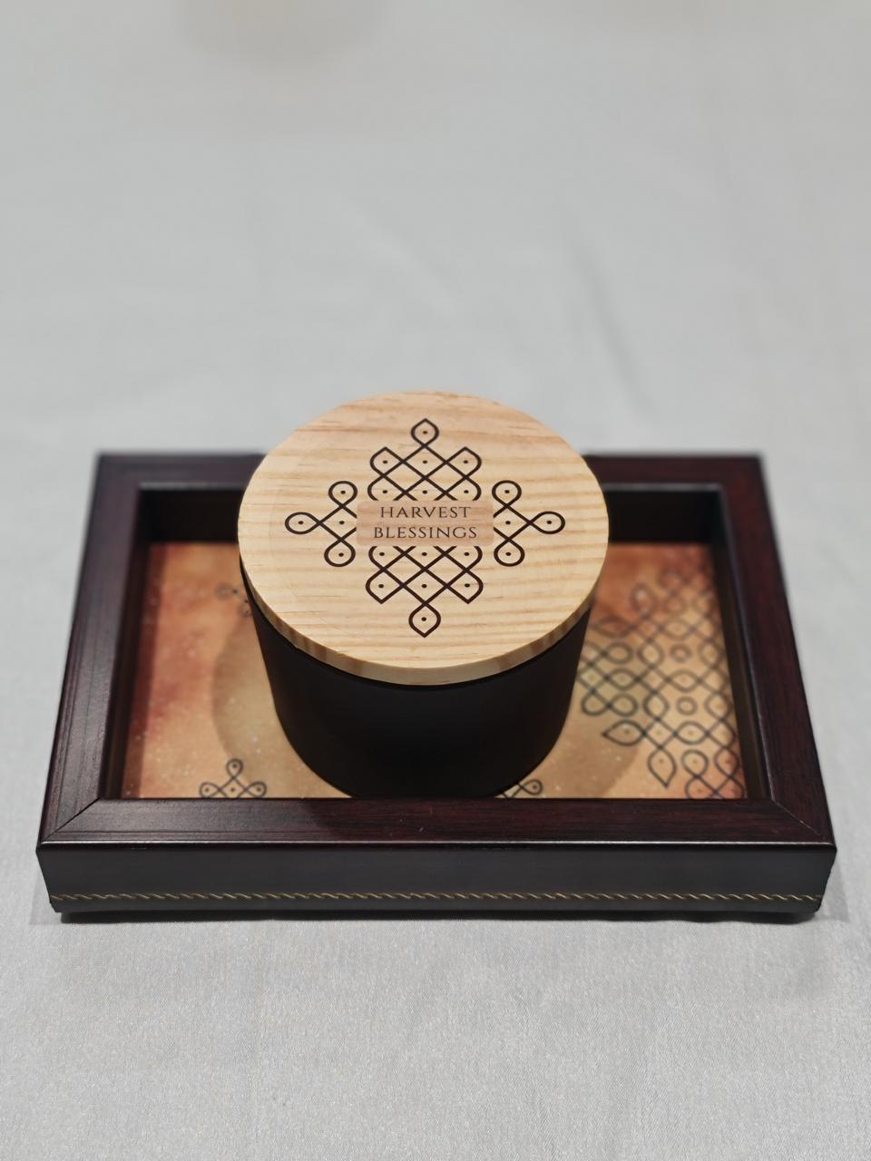 Black container with wooden lid on a decorative tray against a light gray background
