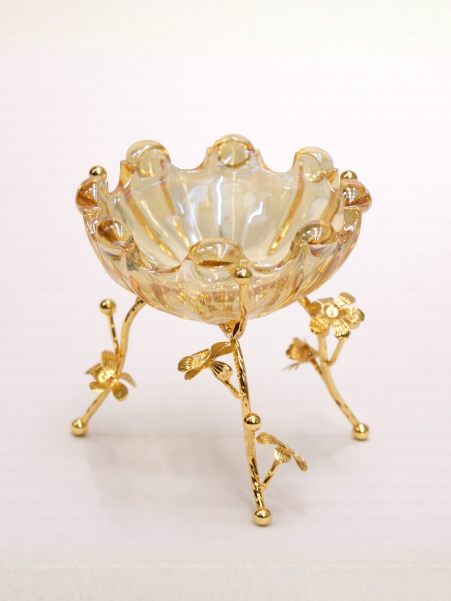 Decorative glass bowl with gold stand on a light pink background