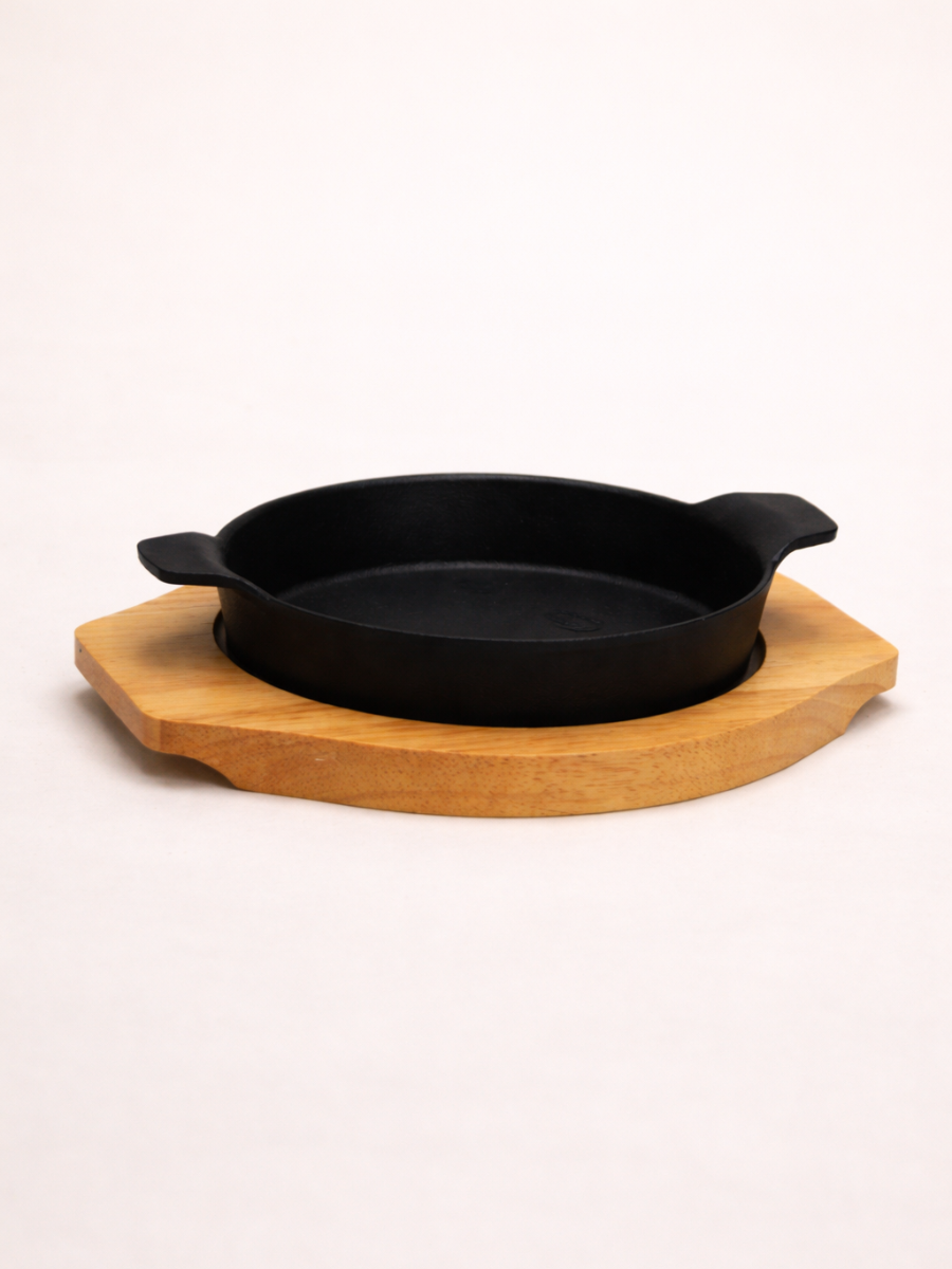 Black cast iron skillet on a wooden trivet against a white background
