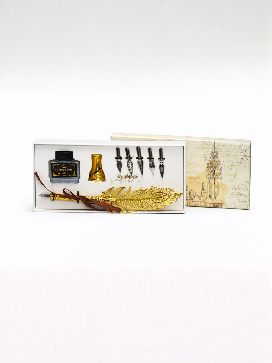Set of quill pens, inkwell, and feather in a decorative box on a white background