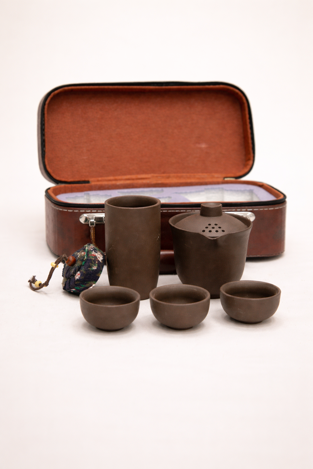 Tea set with four cups and a teapot in an open brown case on a white background
