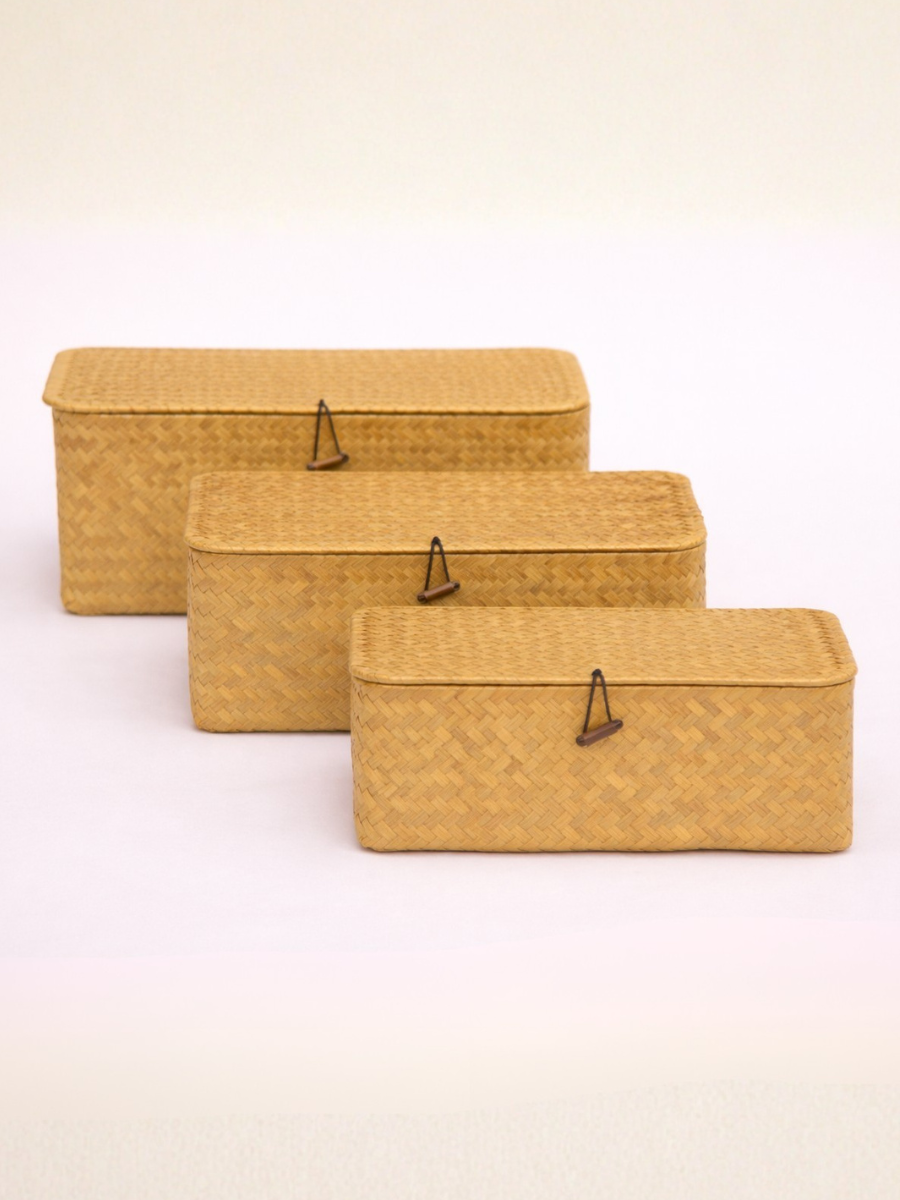 Three mustard yellow woven storage boxes of different sizes on a light beige background