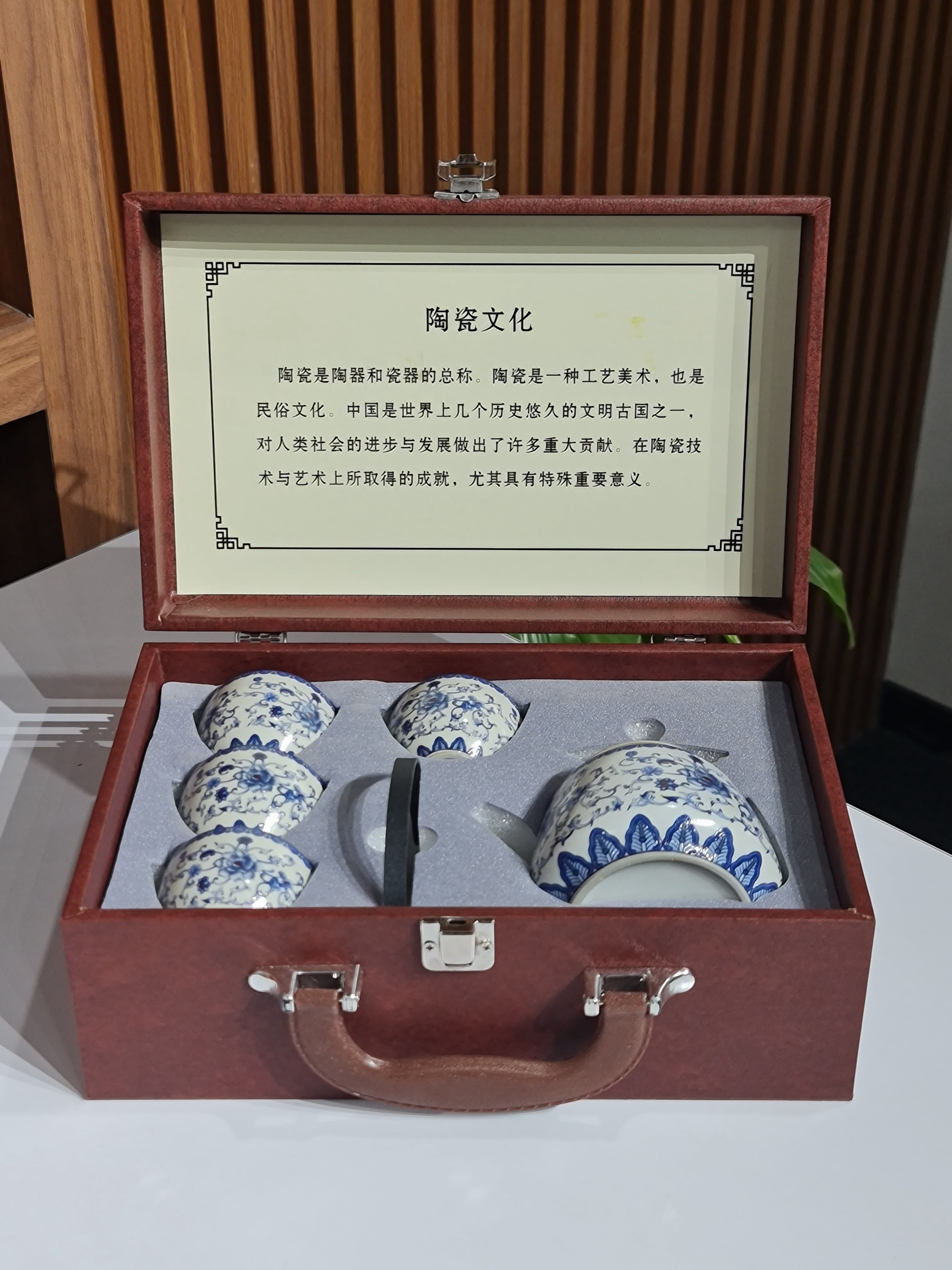 Set of ceramic teapots in a wooden case with an open lid displaying text.