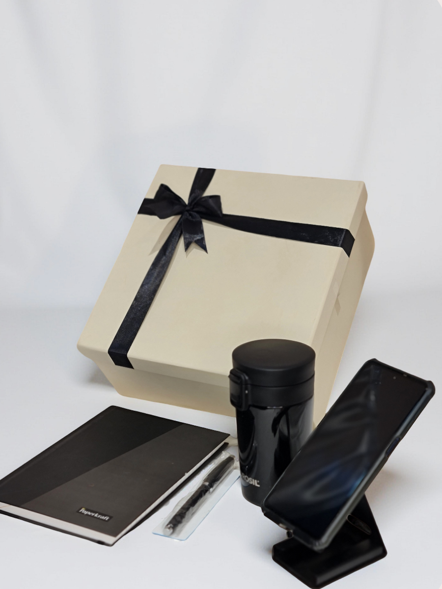 Gift box with black ribbon, black tumbler, and black phone stand on a white background