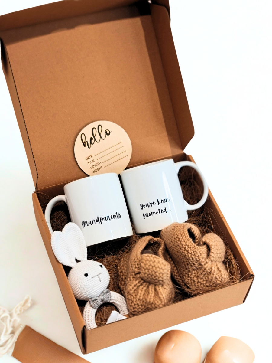 Gift set with two mugs, a plush toy, and knitted items in a box.