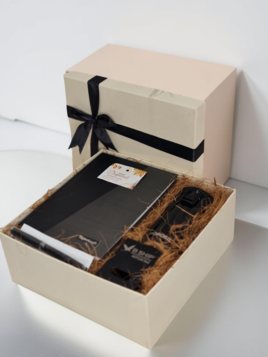 Gift box with black ribbon containing a laptop and other items on a white background