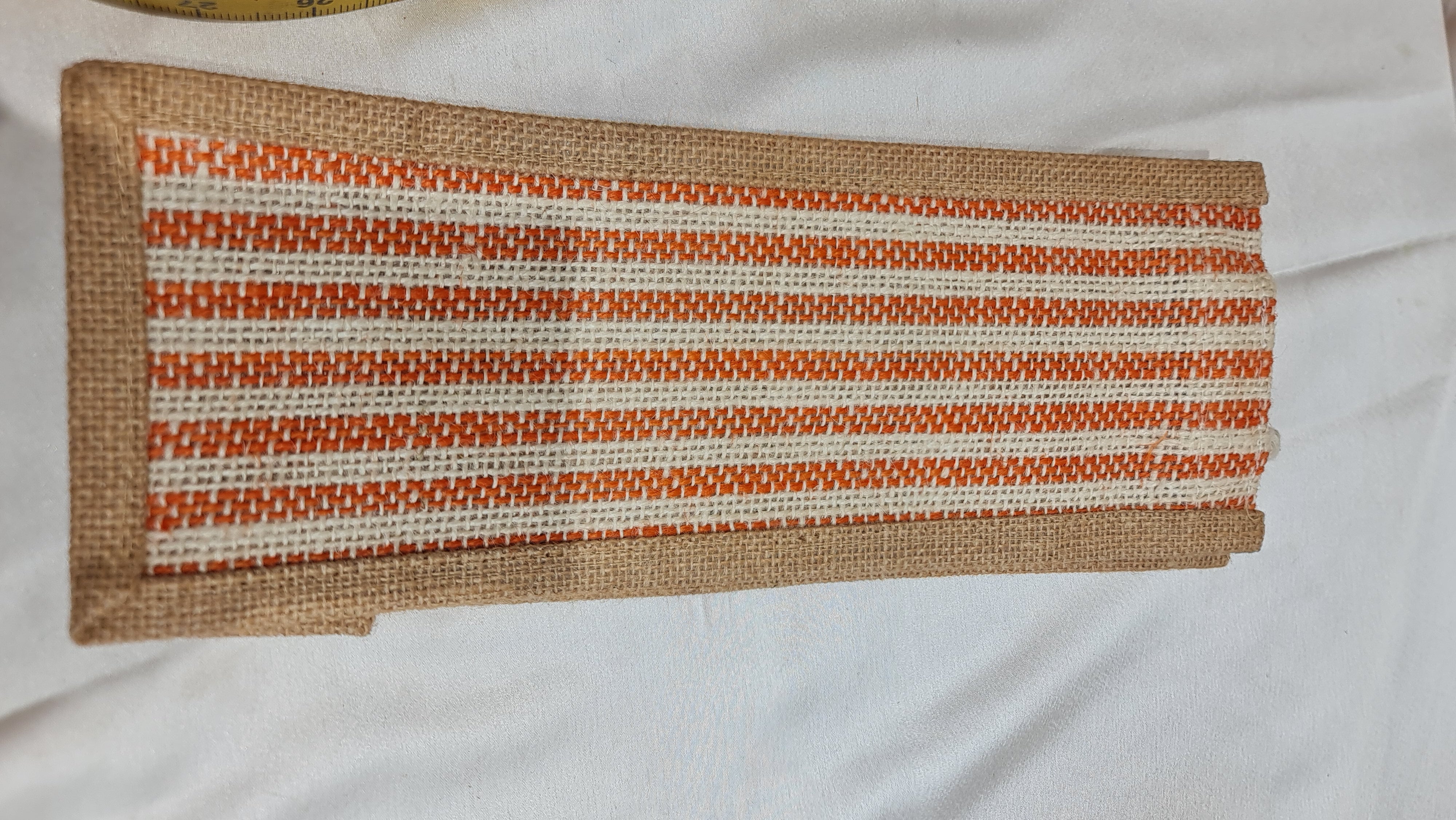 Striped woven mat with orange and beige pattern on a white background