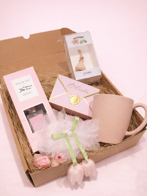 Gift basket with a mug, soap, and other items on a pink background