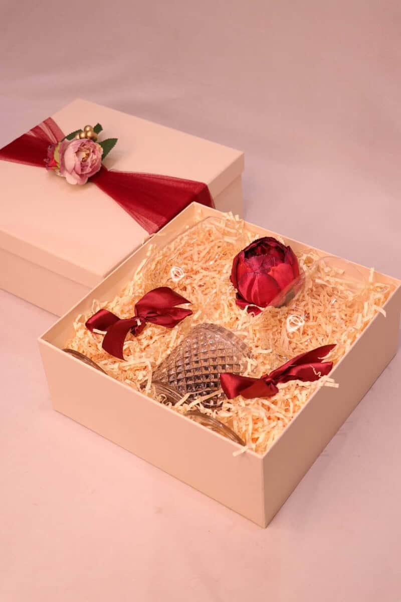 Decorative box with a rose and a small decorative item on a pink background