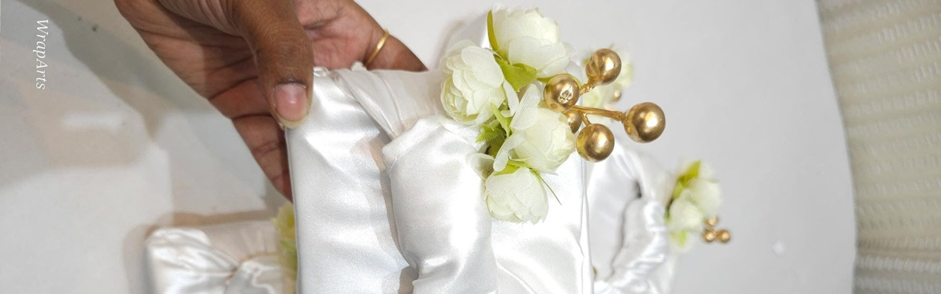 White satin ribbon with white flowers and gold accents on a white background