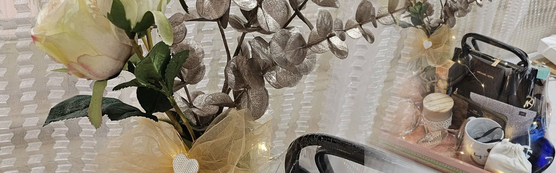 Decorative setup with flowers, a small table, and various items on a textured surface.