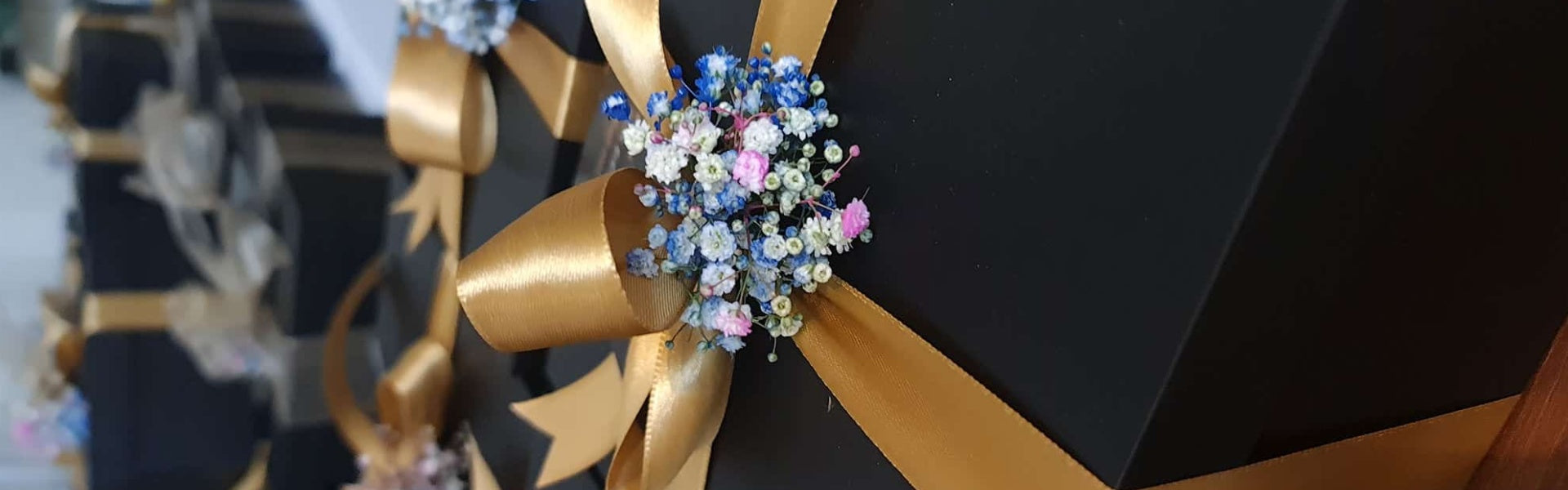 Decorative bow with gold ribbon and blue floral arrangement on a black background
