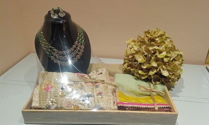 Jewelry set including a necklace, earrings, and a handbag on a mannequin and table.