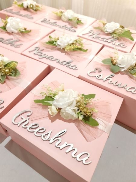 Pink boxes with floral arrangements and names on a light background