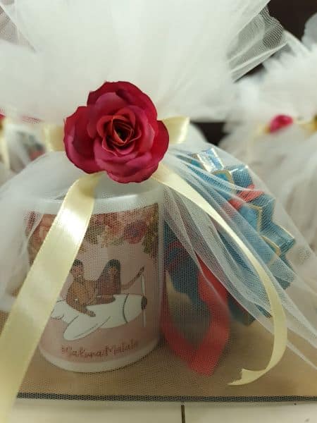 Candle with a red rose on top, wrapped in tulle and ribbons, with a blurred background.