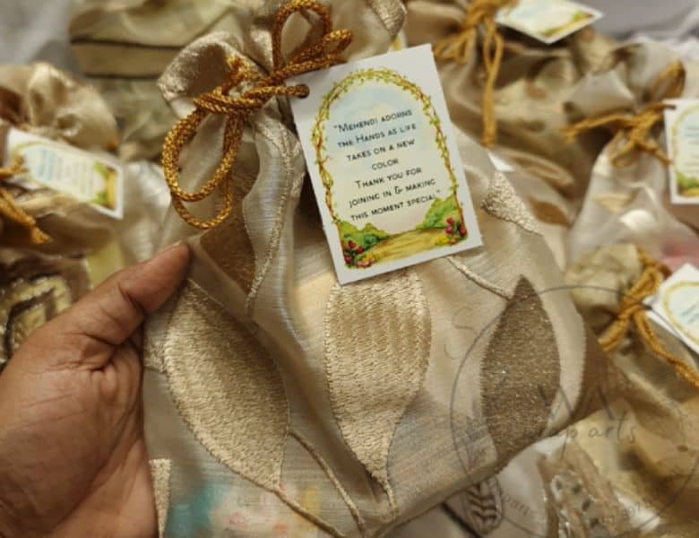 Decorative package with a gold bow and gift tag, held by a hand.