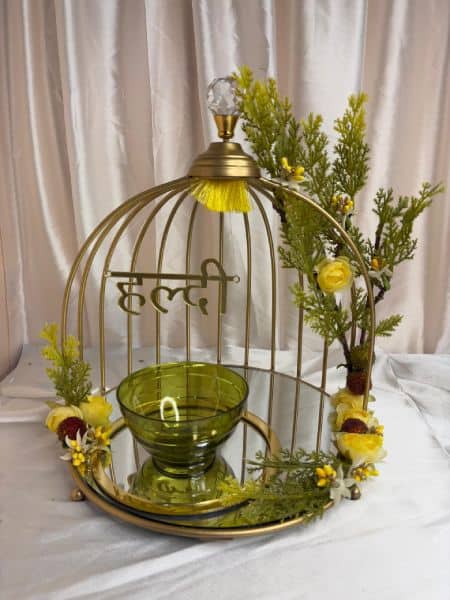 Decorative birdcage with green candle holder and yellow flowers on a white background