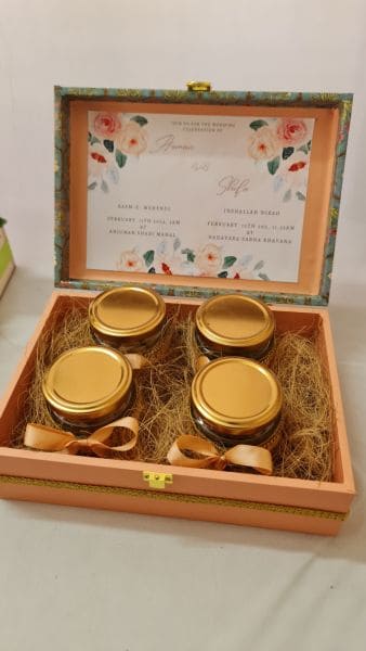 Set of jars with gold lids in a decorative wooden box with floral design on the lid.