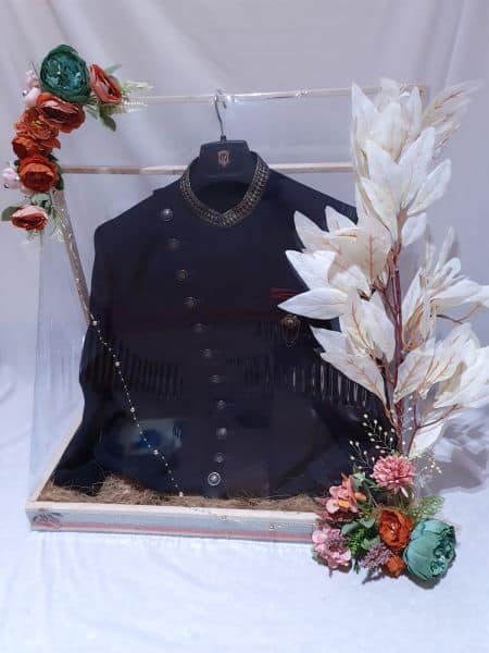 Black coat on a hanger with decorative flowers and plants in a clear box.