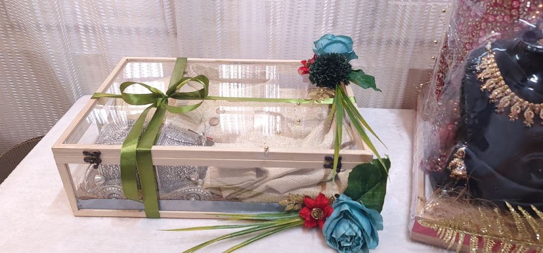 Decorative box with green ribbon and flowers on a white surface